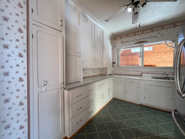 kitchen featuring ceiling fan, decorative backsplash, sink, stainless steel refrigerator, and white cabinetry