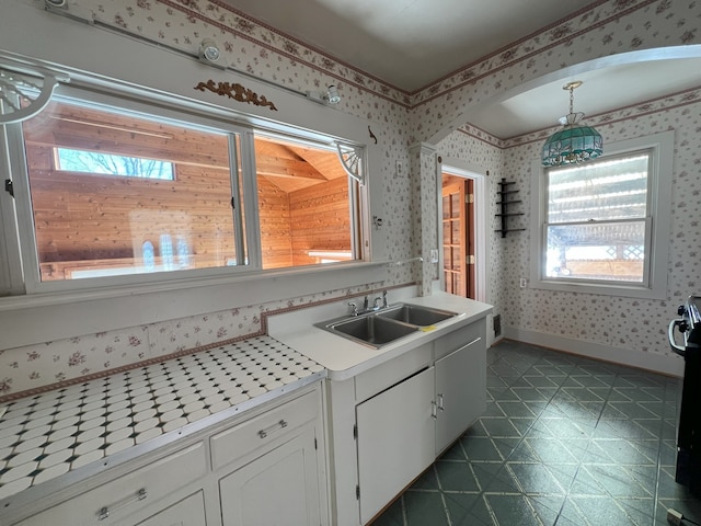 kitchen with decorative light fixtures, sink, white cabinetry, and stove