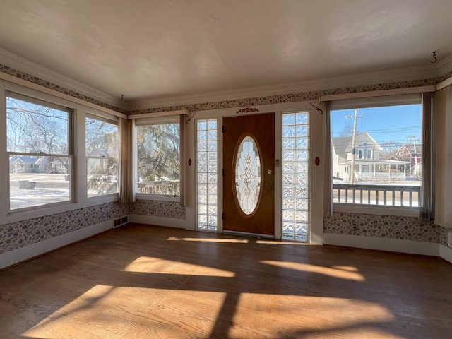 entryway with ornamental molding and wood-type flooring