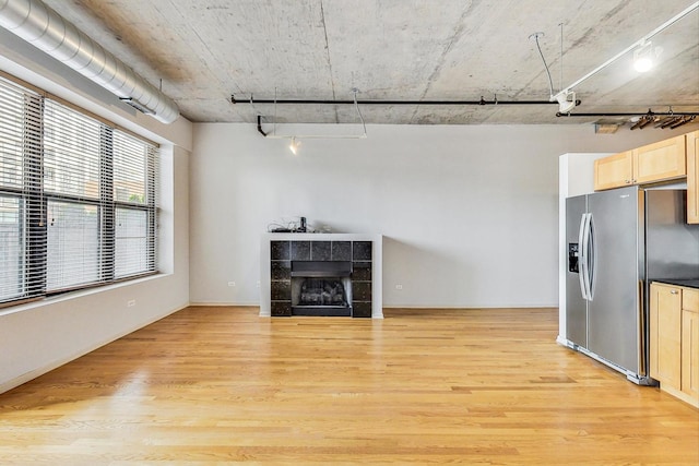 unfurnished living room with light hardwood / wood-style floors and a tile fireplace