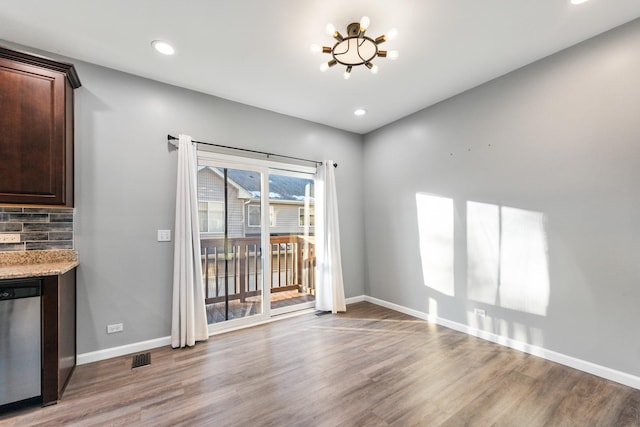 unfurnished dining area featuring wood-type flooring and a chandelier