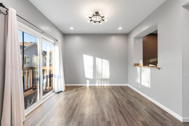 spare room with an inviting chandelier and hardwood / wood-style floors