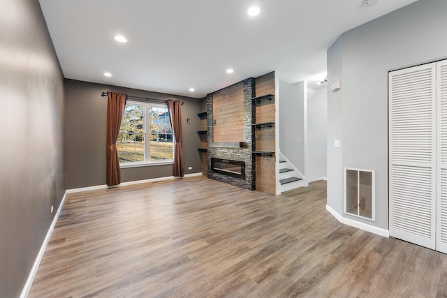 unfurnished living room featuring a stone fireplace and light wood-type flooring