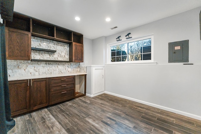 bar featuring tasteful backsplash, dark brown cabinetry, dark hardwood / wood-style floors, and electric panel