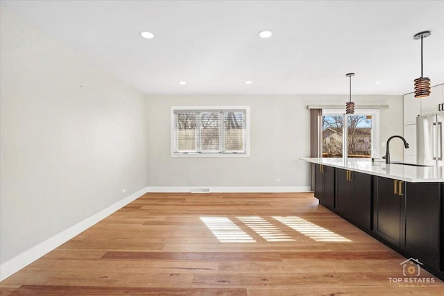 interior space with sink, light hardwood / wood-style flooring, high end refrigerator, and decorative light fixtures