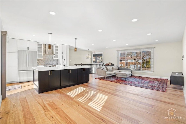 kitchen featuring a large island, hanging light fixtures, stainless steel fridge, and light hardwood / wood-style flooring