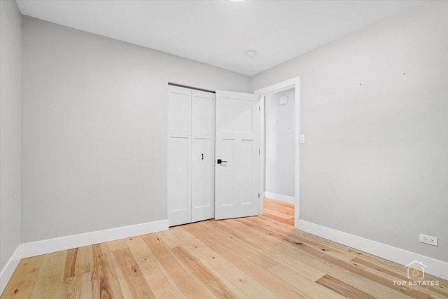 unfurnished bedroom with wood-type flooring and a closet