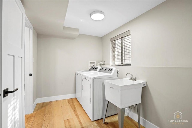 washroom with separate washer and dryer, sink, and light hardwood / wood-style flooring