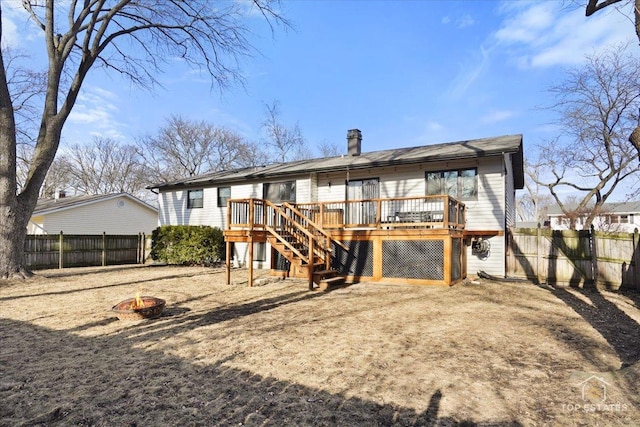 rear view of house with a wooden deck and a fire pit