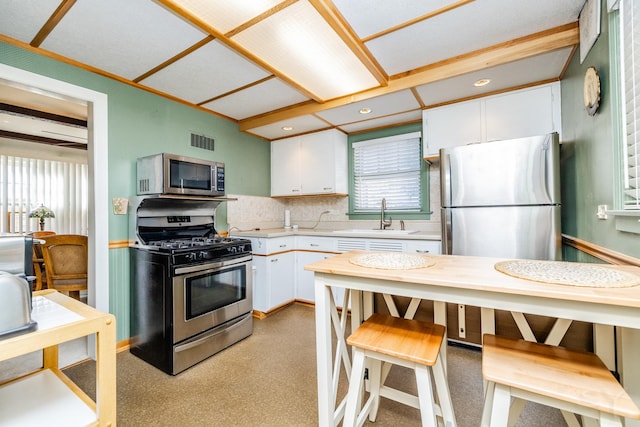 kitchen with white cabinetry, stainless steel appliances, decorative backsplash, sink, and a kitchen breakfast bar