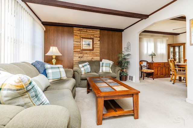 carpeted living room with beam ceiling and wood walls