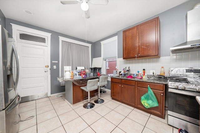 kitchen featuring wall chimney range hood, decorative backsplash, sink, stainless steel appliances, and light tile patterned floors