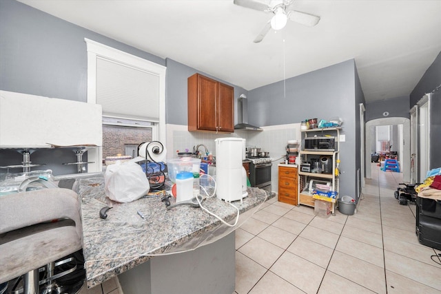 kitchen featuring light tile patterned floors, kitchen peninsula, ceiling fan, tasteful backsplash, and wall chimney exhaust hood