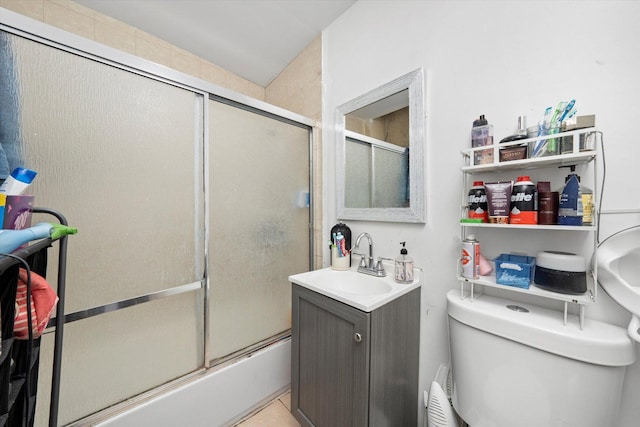 full bathroom featuring toilet, bath / shower combo with glass door, tile patterned flooring, and vanity