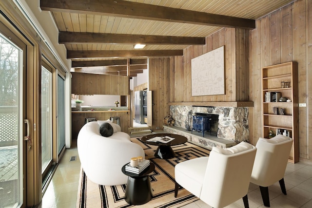 living room featuring a fireplace, wooden walls, and beamed ceiling