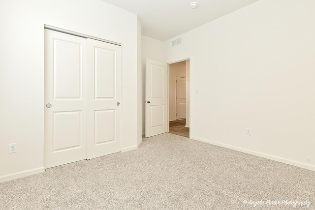 unfurnished bedroom featuring light colored carpet and a closet