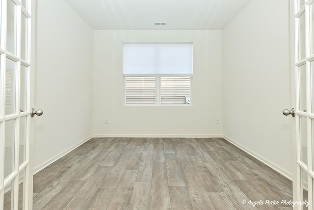 spare room with french doors and light hardwood / wood-style flooring