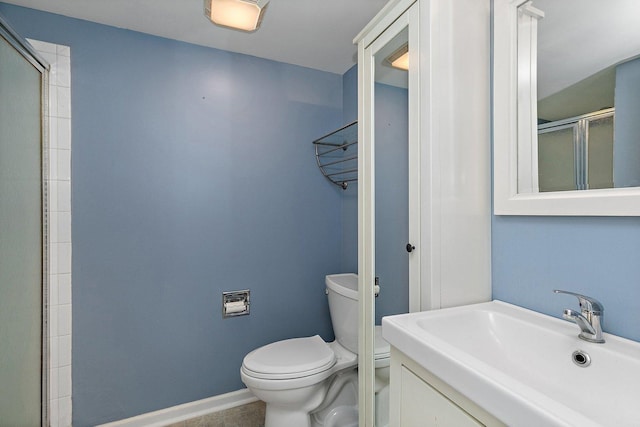 bathroom featuring a shower with door, sink, and toilet