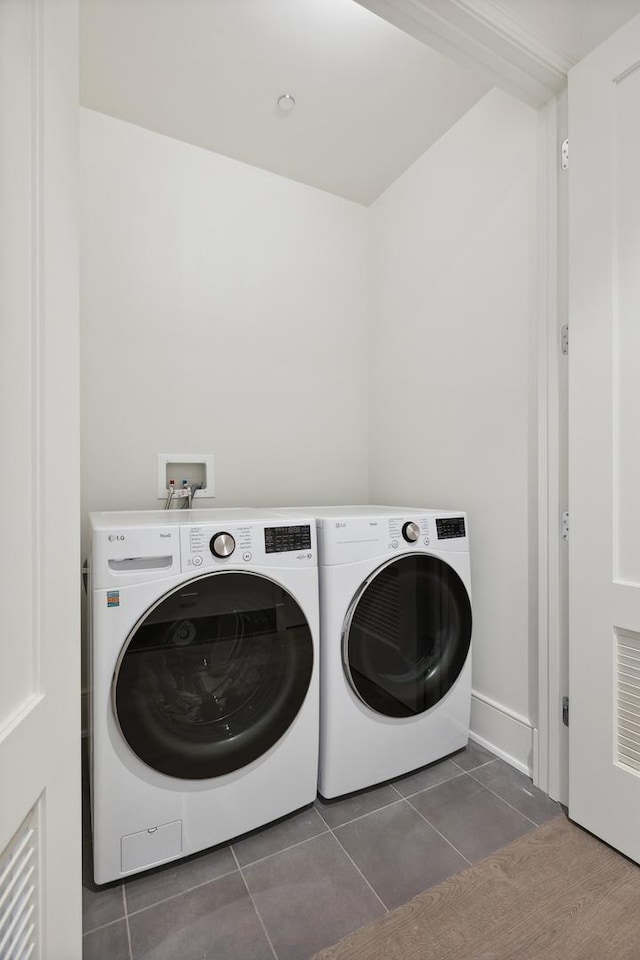 clothes washing area with dark tile patterned flooring and independent washer and dryer