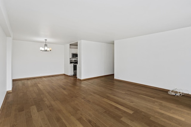 unfurnished living room featuring dark wood-type flooring and an inviting chandelier