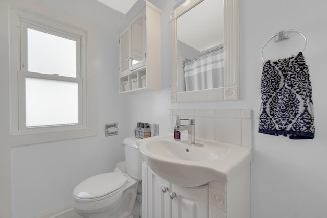 bathroom featuring toilet, vanity, and curtained shower