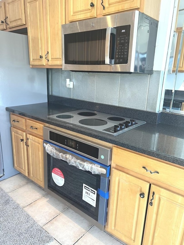 kitchen with decorative backsplash, appliances with stainless steel finishes, and light tile patterned flooring