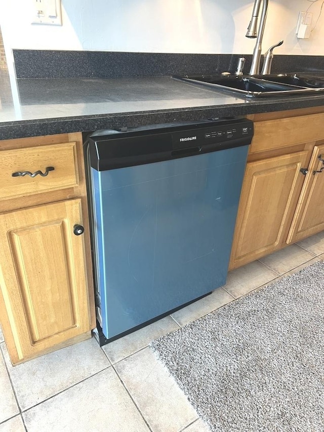 kitchen featuring sink, dishwashing machine, and light tile patterned floors