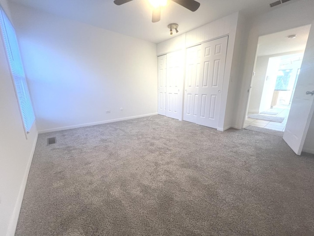 unfurnished bedroom featuring ceiling fan, carpet, and a closet