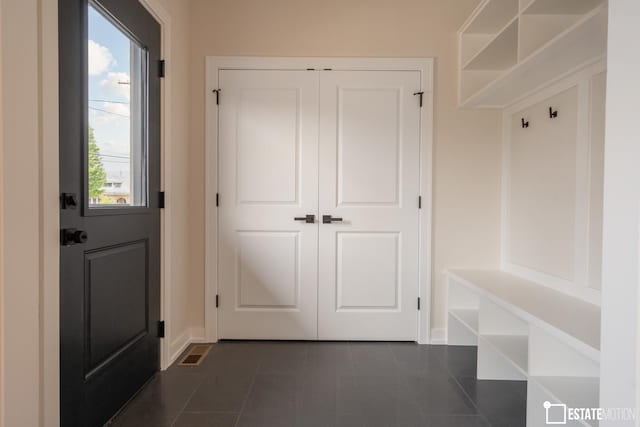 mudroom with dark tile patterned floors