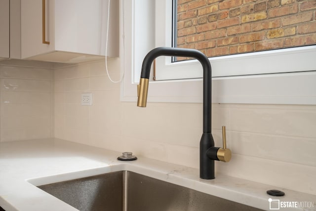 room details with light stone countertops, white cabinets, sink, and tasteful backsplash