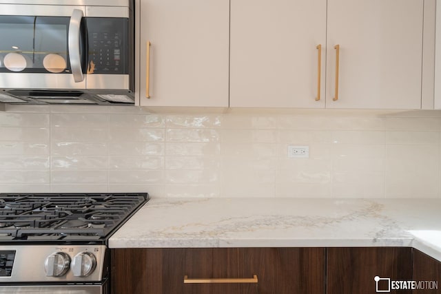 kitchen featuring decorative backsplash, light stone counters, stainless steel appliances, and dark brown cabinetry