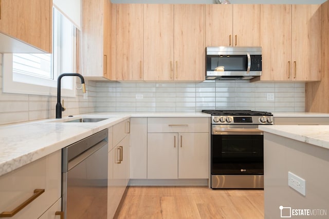 kitchen with light stone countertops, sink, light brown cabinets, and stainless steel appliances