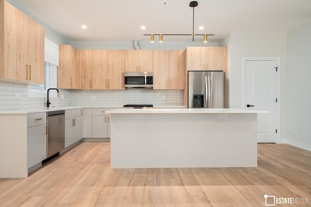 kitchen with light brown cabinetry, pendant lighting, appliances with stainless steel finishes, and a kitchen island