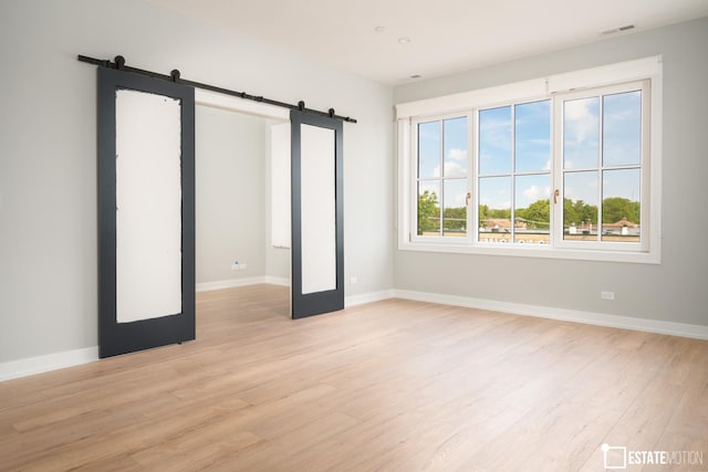 unfurnished bedroom featuring light hardwood / wood-style floors and a barn door