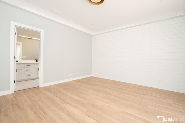 spare room with light wood-type flooring, sink, and crown molding