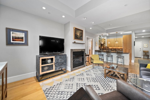 living room featuring a tray ceiling, light hardwood / wood-style flooring, and a tile fireplace