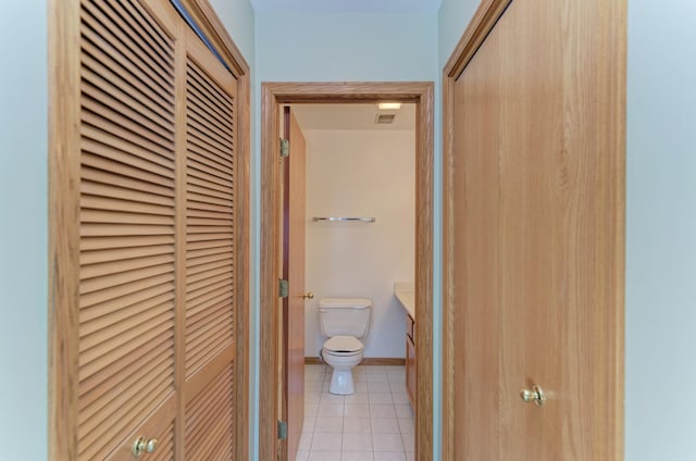 bathroom featuring a closet, tile patterned flooring, toilet, and baseboards