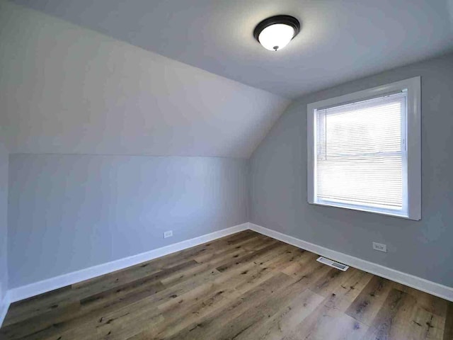 additional living space with vaulted ceiling and wood-type flooring