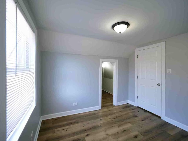 additional living space featuring dark wood-type flooring and lofted ceiling