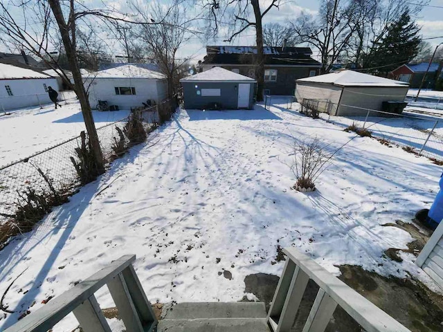 snowy yard with a garage and an outbuilding