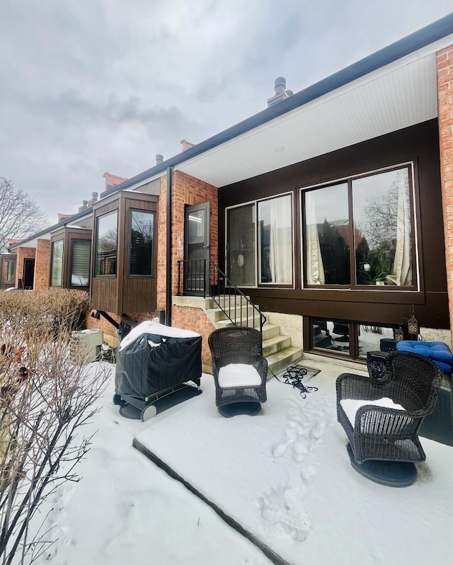 snow covered house featuring a patio area