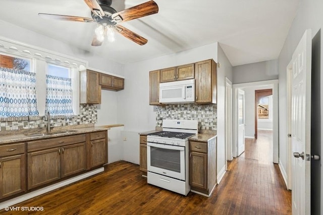 kitchen with sink, white appliances, dark wood-type flooring, and decorative backsplash