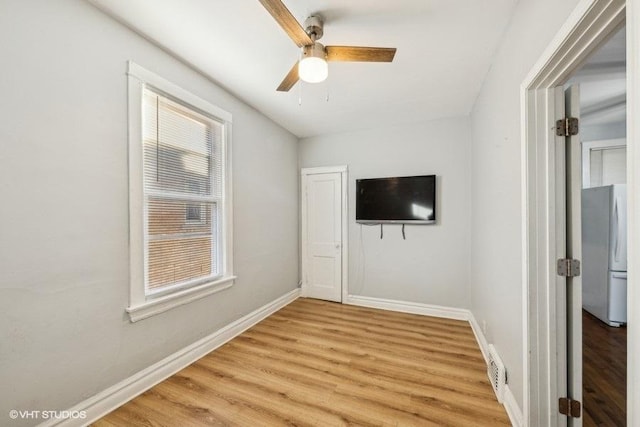 unfurnished bedroom with fridge, ceiling fan, and hardwood / wood-style flooring