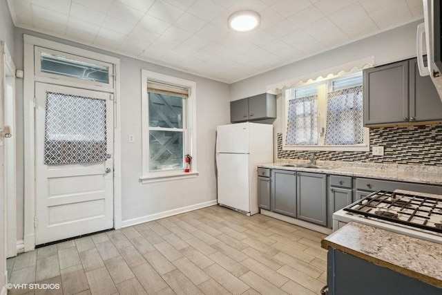 kitchen with gray cabinets, sink, decorative backsplash, white refrigerator, and light hardwood / wood-style floors