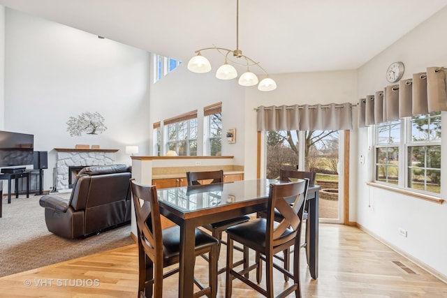 dining space with light wood-type flooring, a fireplace, visible vents, and baseboards