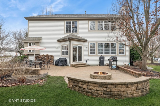 rear view of property with entry steps, a patio area, an outdoor fire pit, and a lawn