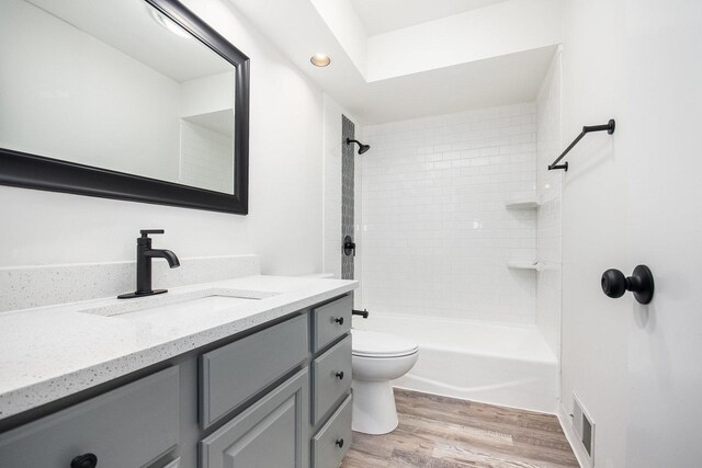 full bathroom with toilet, vanity, wood-type flooring, and tiled shower / bath combo