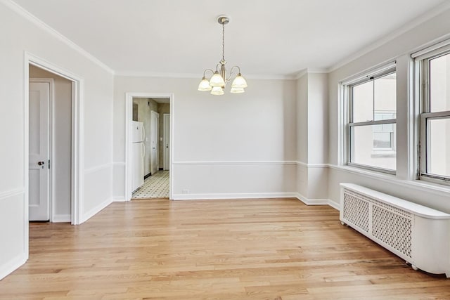 empty room with crown molding, radiator, a chandelier, and light hardwood / wood-style floors