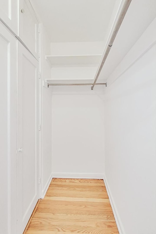 walk in closet with light hardwood / wood-style floors