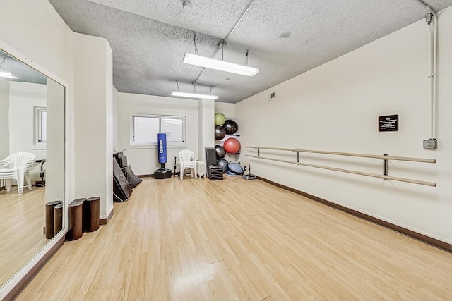 workout area with hardwood / wood-style floors and a textured ceiling